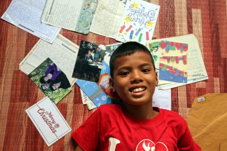 Garçon souriant à côté des lettres de son parrain.