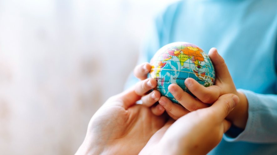 Petites mains tenant un globe terrestre.