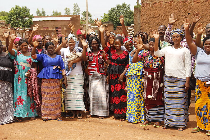 Photo de groupe où les personnes lèvent les mains.