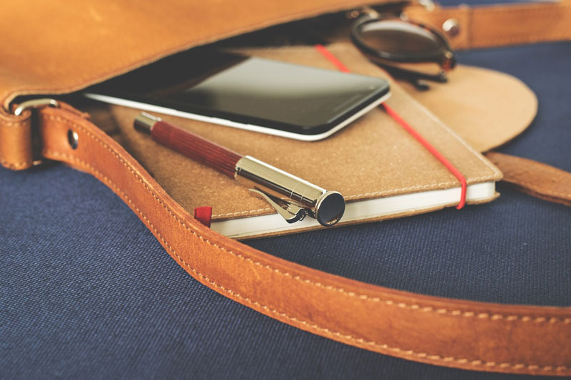 Sac à main avec un smartphone, un stylo et des lunettes de soleil