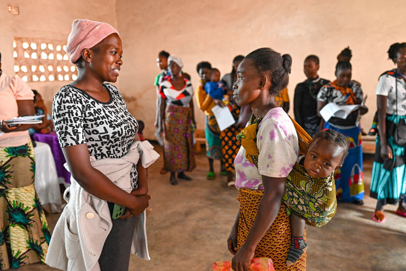 Image montrant deux femmes en pleine discussion, dont l'une portant un enfant sur son dos. Image montrant deux femmes en pleine discussion, dont l'une portant un enfant sur son dos.