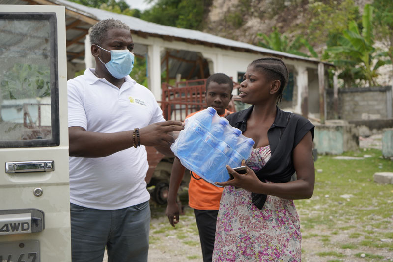 Femme tendant un pack d'eau à un homme chargeant un véhicule. Femme tendant un pack d'eau à un homme chargeant un véhicule.