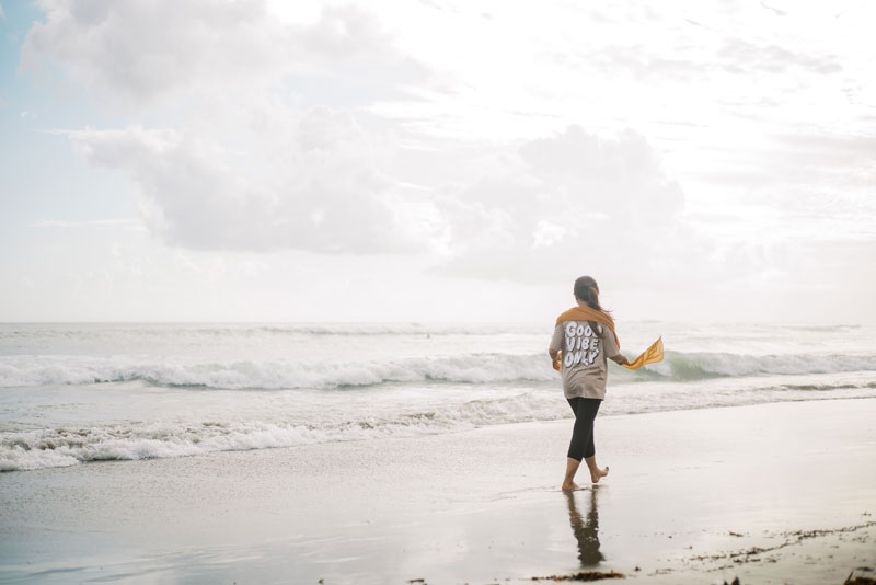Image d'une femme marchant sur le sable, au bord de la mer.