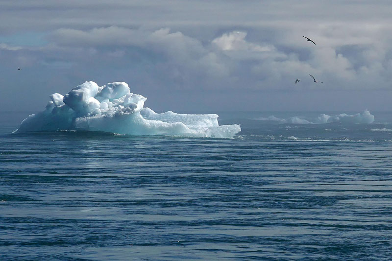Image d'un iceberg sous un ciel nuageux.