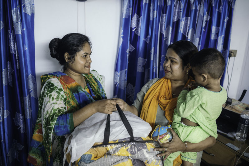 Deux femmes échangeant un sac, l'une portant un enfant.