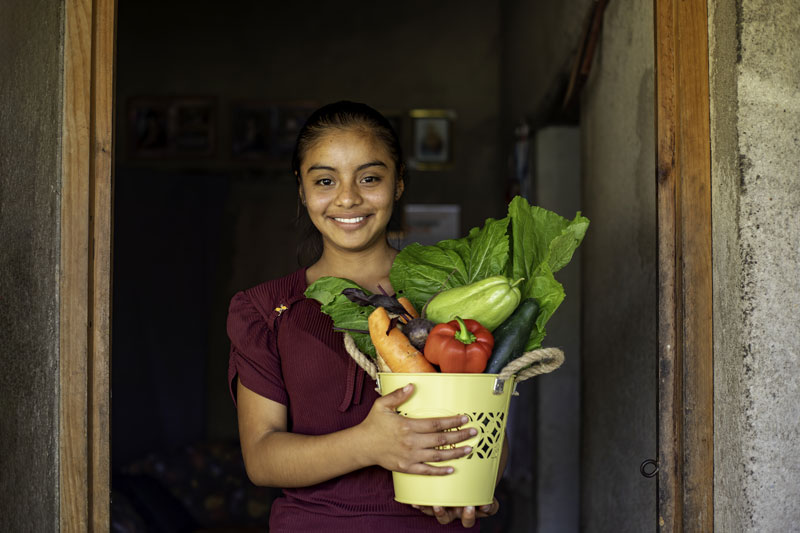 Petite fille souriante tenant un pot rempli de légumes. Petite fille souriante tenant un pot rempli de légumes.